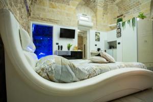 Ce lit se trouve dans un dortoir doté d'une chaise blanche. dans l'établissement Suite Le Dimore di Talos, à Ruvo di Puglia