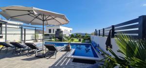 a patio with chairs and an umbrella and a pool at MEERBLICK DUPLEX POOL-VILLA REGIRMA DELUXE bis 8 Personen in Vodice