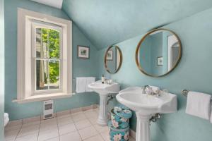 a blue bathroom with two sinks and a mirror at Manoir Sweetsburg in Cowansville