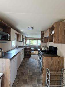 a kitchen with wooden cabinets and a stove top oven at Caravan Turnberry 2 in Port Seton