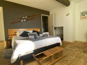 a bedroom with a large bed and a wooden bench at Les Chambres des 3 Chouettes in Sepx