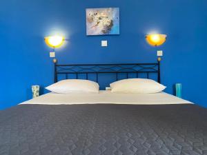 a blue bedroom with a large bed with two pillows at Daphne Bungalows in Tolo