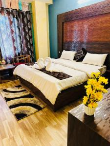 Hotel Tara Regency - A family Hotel في شيملا: غرفة نوم بسرير كبير وطاولة مع ورد