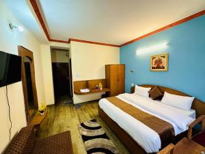 Hotel Tara Regency - A family Hotel في شيملا: غرفة نوم بسرير كبير بجدار ازرق