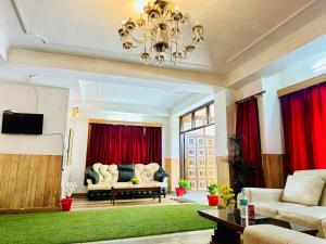 ein Wohnzimmer mit einem Kronleuchter und roten Vorhängen in der Unterkunft Hotel Tara Regency - A family Hotel in Shimla