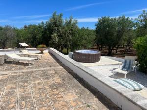 a patio with a fire pit and chairs and trees at Trullo La Quercia in Ostuni