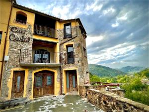 un antiguo edificio de piedra con puertas y un balcón en Can Castell, en Castellfollit de la Roca