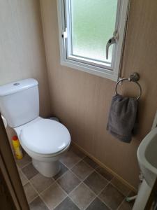 a small bathroom with a toilet and a window at Caravan Turnberry 2 in Port Seton