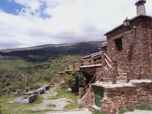 an old stone building on a hill with mountains in the background at Apartamentos Balcon del Cielo in Trevélez