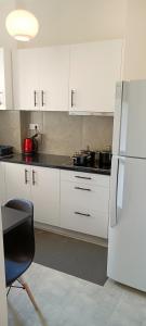 a kitchen with white cabinets and a chair and a refrigerator at Candy Studio Apt Marousi in Athens