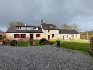 a large stone house with red doors and a yard at Gîte Comme chez Ti in Rostrenen