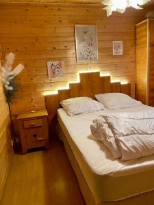 - une chambre avec un lit et un mur en bois dans l'établissement Chalet des Moineaux, à Saint-Laurent-du-Jura