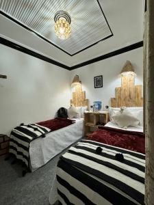 1 dormitorio con 2 camas y lámpara de araña en RIAD dreams dades en Tamellalt