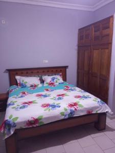 a bed with a floral comforter in a bedroom at Comfort Zone Apartment in Yaoundé