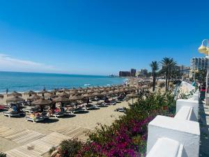 a beach with umbrellas and chairs and the ocean at Luxury beachfront apartment in Benalmadena Costa in Benalmádena