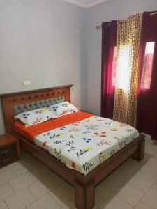 a bedroom with a bed with an orange comforter at Comfort Zone Apartment in Yaoundé