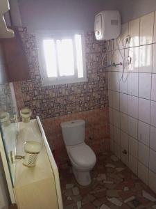 a bathroom with a toilet and a window in it at Comfort Zone Apartment in Yaoundé