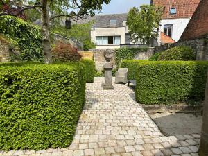 a garden with a stone walkway with a statue and bushes at Maison Gaston in Bruges +34 photos