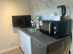 um balcão de cozinha com um micro-ondas e um lavatório em Cosy em Mechelen