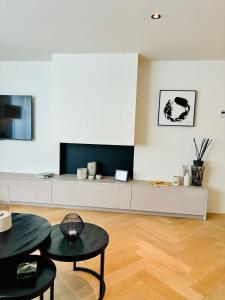 - un salon avec deux tables et une télévision dans l'établissement Sejoylia Knokke: app 2ch luxueux au centre de KH, à Knokke-Heist