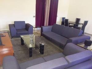 a living room with purple couches and a table at Comfort Zone Apartment in Yaoundé