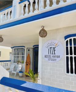 un cartel en la parte delantera de una casa con una tabla de surf en Itzé Hostel Boutique - Progreso, en Progreso