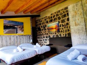 Habitación con 3 camas y pared de piedra. en Can Castell, en Castellfollit de la Roca