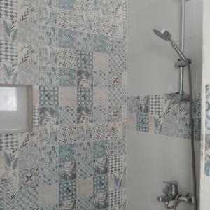 y baño con ducha y pared de azulejos. en desert pearl beautiful cosy new home, en Luxor