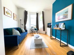 a living room with blue walls and a blue couch at Broomsleigh NW6 Apartment in London