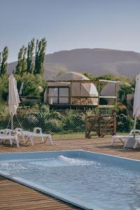 a swimming pool with two chairs and a gazebo at Glamping Puente Blanco in Sierra de la Ventana