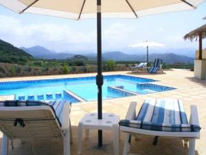 a pool with two chairs and an umbrella at Terramara in Nohia