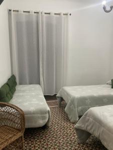 Habitación con 2 camas, silla y cortinas en La magnolia en La Puerta de Segura