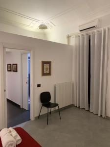 um quarto com uma cadeira preta e uma parede branca em Corso Vittorio Giuliano Family em Palermo