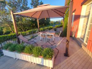 a patio with a table and chairs under an umbrella at Agriturismo IL BIANCOSPINO Bed & Wine in Lerma