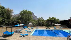 ein Schwimmbad mit blauen Liegestühlen und Sonnenschirmen in der Unterkunft Sampaz in Tepoztlán