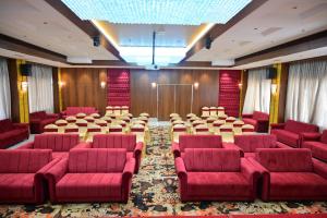 a conference room with red chairs and tables in it at Hotel Golden Riviera in Mysore