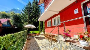 czerwony dom z krzesłami i parasolem w obiekcie Valea Albă View - SELF CHECK-IN w mieście Buşteni