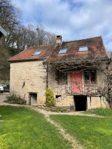 ein altes Steinhaus mit einer roten Tür in der Unterkunft Ô Bonheurs Simples d'Ecorsaint Ici Doucement in Hauteroche