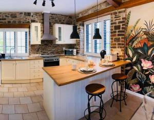 a kitchen with white cabinets and a island with bar stools at Captain‘s Cottage in Llandeilo