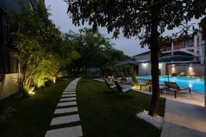 a garden with a pathway next to a swimming pool at Kobuleti Garden Inn in Kobuleti