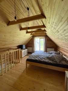Cette chambre en bois comprend un grand lit et une fenêtre. dans l'établissement ШОВКОВА КОСИЦЯ, à Rakhiv