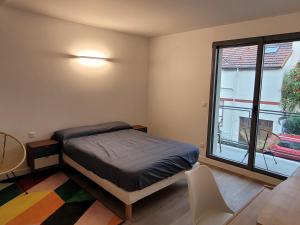 um quarto com uma cama e uma grande janela em Malakoff T2 Rue em Malakoff