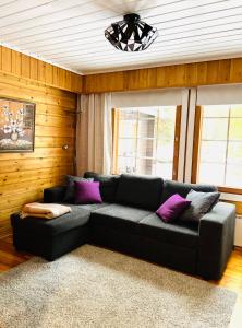 Sofá negro en una sala de estar con almohadas moradas en Susitupa 5 en Salla