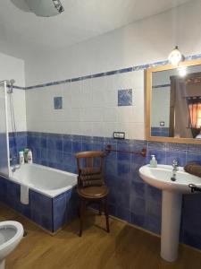 uma casa de banho com uma banheira, uma cadeira e um lavatório. em La magnolia em La Puerta de Segura