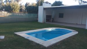 a swimming pool in a yard next to a house at Quinta El Pinar Tenis in San Nicolás de los Arroyos