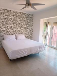 a bedroom with a large white bed with a ceiling fan at Villa Matisse Luxury Beach in Torremolinos
