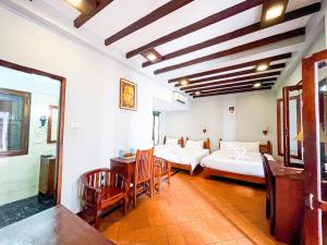 a room with two beds and a table and chairs at khong kham Hotel in Luang Prabang