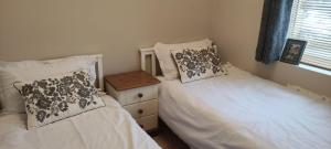 a bedroom with two beds and a night stand at Bow Cottage in Abercraf