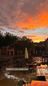 Arens de Lledó的住宿－LA SOCIEDAD，日落时分,配有桌椅和雨伞