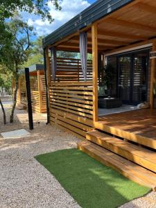 eine Holzhütte mit einer Veranda und grünem Gras in der Unterkunft Mobile Home La Vida in Biograd na Moru